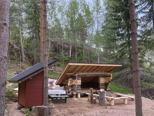 a log cabin in the woods with a wooden roof at Lammastilan laavu - Lean to Inarin tila in Salo