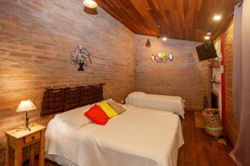 a bedroom with two beds and a brick wall at Pousada das Acácias in Camanducaia