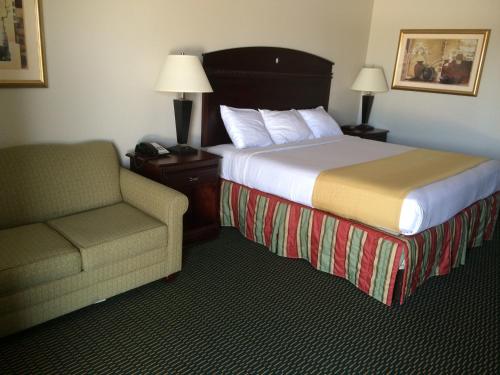 a hotel room with a bed and a chair at Express Inn in Wharton