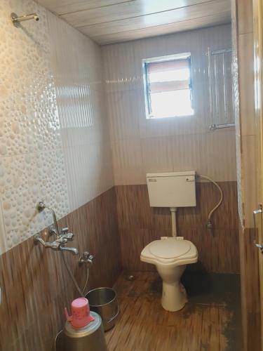 a small bathroom with a toilet and a window at Hiral residency in Matheran