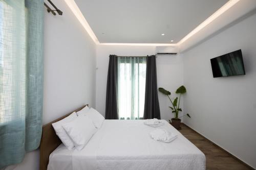 a bedroom with a bed with white sheets and a window at Maistros Apartments Mykonos in Elia