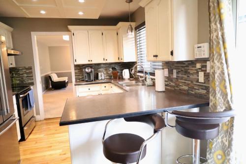 a kitchen with a counter and two stools at Sandy Hill Retreat - 3 Bedroom + Den, 2 Bath House with Fitness Equipment in Abbotsford