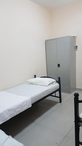a white room with a bed and a locker at AJ Hostel in Dubai