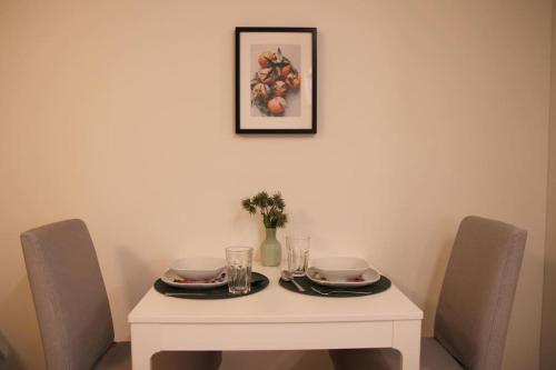 una mesa blanca con dos platos y vasos. en Kodikas hyvin varusteltu yksiö, autopaikalla, en Vantaa