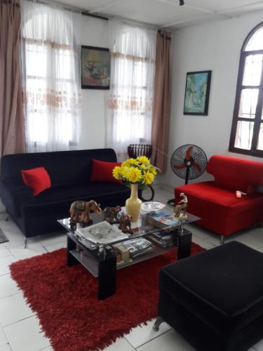 a living room with a black couch and red furniture at VIVIENDA TURISTICA ROYAL INN in Barranquilla