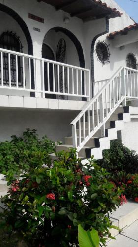 a white house with a staircase and a bush at VIVIENDA TURISTICA ROYAL INN in Barranquilla