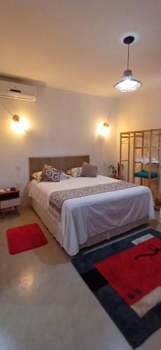 a bedroom with a large bed with red rugs at Casa Versel Trancoso in Trancoso