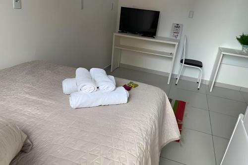 a bedroom with a bed with two rolled towels at Apartamentos centrais junto ao calçadão in Ponta Grossa