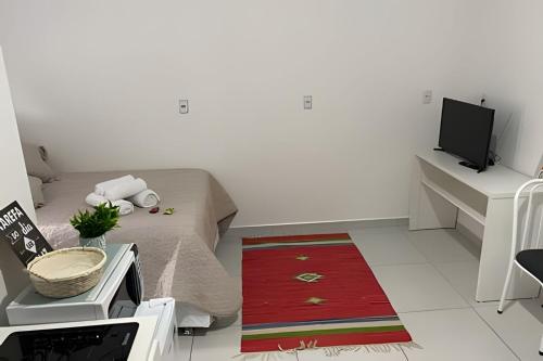 a living room with a bed and a tv at Apartamentos centrais junto ao calçadão in Ponta Grossa