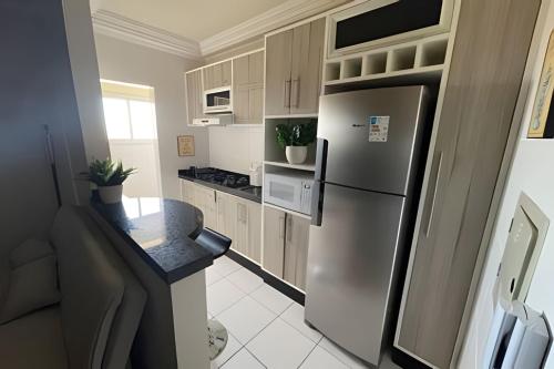 uma cozinha com um frigorífico de aço inoxidável e um balcão em Apartamento 2 quartos c/ garagem em Ponta Grossa
