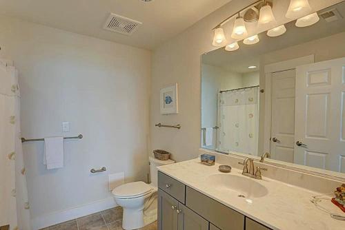a bathroom with a sink and a toilet and a mirror at TSC203 Fisher Oceanfront Elevator in Kill Devil Hills