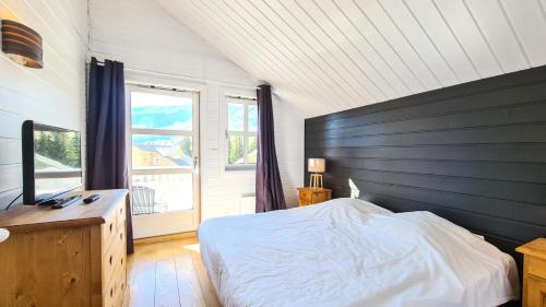 une chambre avec un lit et une grande fenêtre dans l'établissement Résidence Hameau - Chalets pour 8 Personnes 59, à Flaine