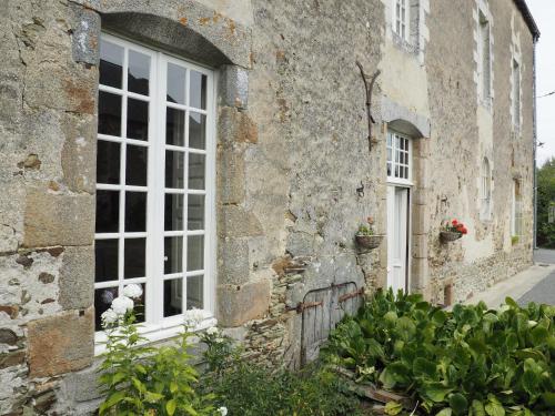 Cossé-le-VivienにあるLes Grands-Aulnaisの窓と植物のある古い石造りの建物
