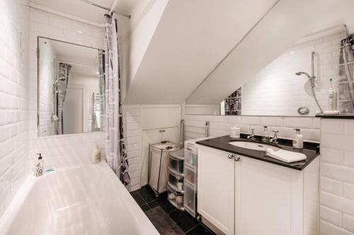 ein weißes Badezimmer mit einer Badewanne und einem Waschbecken in der Unterkunft Inviting 1BD Hideaway Kensington Olympia! in London
