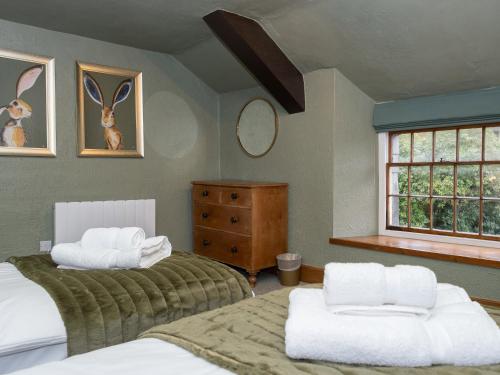 1 Schlafzimmer mit 2 Betten, einer Kommode und einem Fenster in der Unterkunft Watermouth Castle, Rhododendron Apartment in Ilfracombe