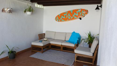 a living room with a couch and a surfboard on the wall at Casa Mar Azul. in Tinajo