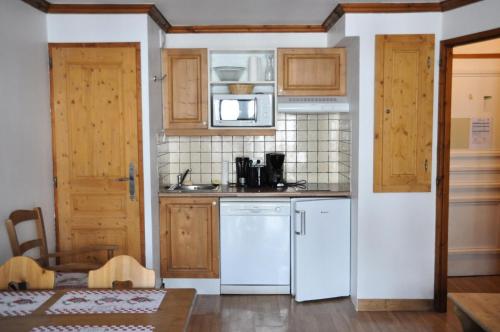 - une petite cuisine avec des appareils blancs et des armoires en bois dans l'établissement Résidence Gentiane Hameau De La Vallee D'or - 2 pièces 4 personnes 3 expo sud ouest MAE-8074, à Valloire