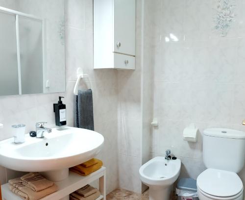 uma casa de banho branca com um lavatório e um WC em Sol, mar y arena em Torrevieja