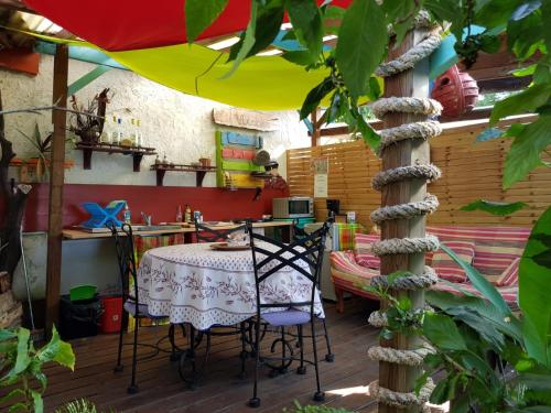 un patio con mesa y sillas bajo una sombrilla en L'Atelier Gîtes des Koalas, en Terre-de-Bas
