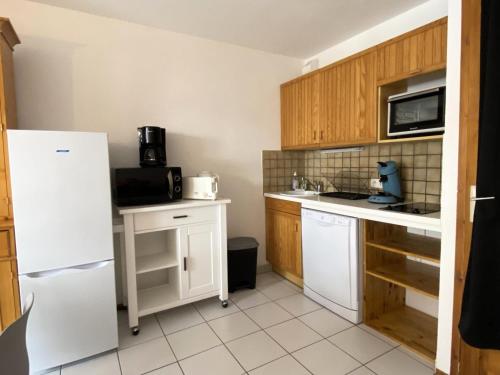 une cuisine avec des armoires en bois et un réfrigérateur blanc dans l'établissement Residence Tigny - 2 pièces cabine 4 personnes exposé sud MAE-8754, à Valloire