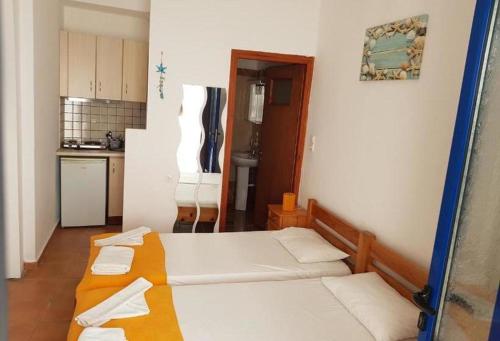 una camera con 2 letti e una cucina con frigorifero di Lydia Mare ad Agios Kirykos