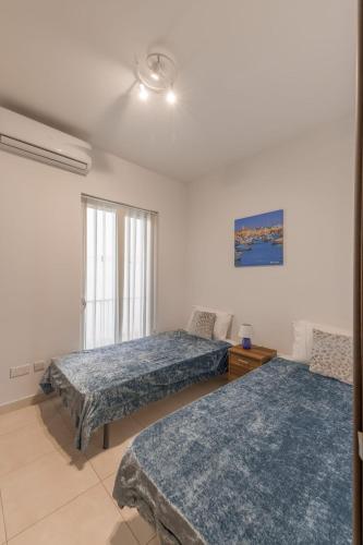 a bedroom with two beds and a window at The Pinnacle Fl6 city escape by Homely in Mellieħa