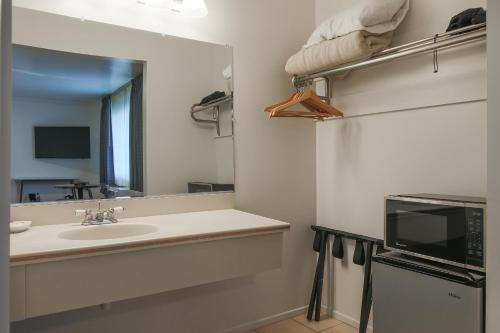 a bathroom with a sink and a mirror and a microwave at Solvang Inn & Cottages in Solvang
