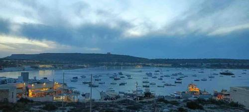 a harbor with boats in the water at dusk at Mellieha Bay Seafront With Spectacular Views3bed in Mellieħa