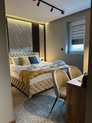a bedroom with a large bed and two chairs at MOZAIK APARTMENTS & SPA - Modern 4-Star Apartments with Exclusive Private SPA WELLNESS in the City Center - SAUNA, JACUZZI, TURKISH BATH - FREE PARKING, Wi-FI - Rooms & Apartments Cuprija in Ćuprija