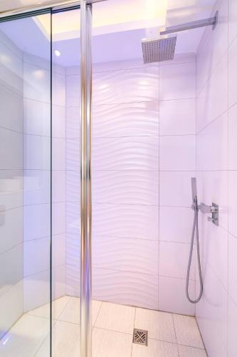 a shower with a glass door in a bathroom at Mellieha Bay Designer Apartment by Homely in Mellieħa