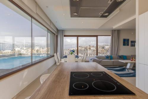 a living room with a table and a large window at Luxury PH with rooftop pool in Mellieha by Homely in Mellieħa