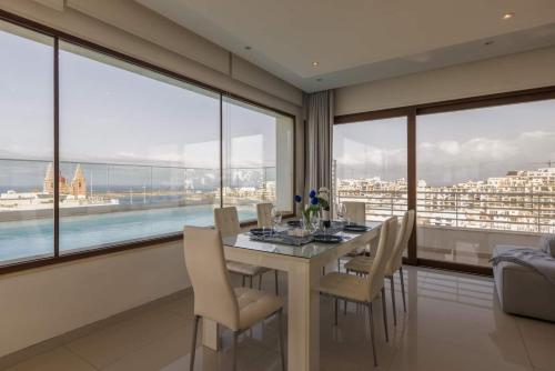 a dining room with a table and chairs and large windows at Luxury PH with rooftop pool in Mellieha by Homely in Mellieħa