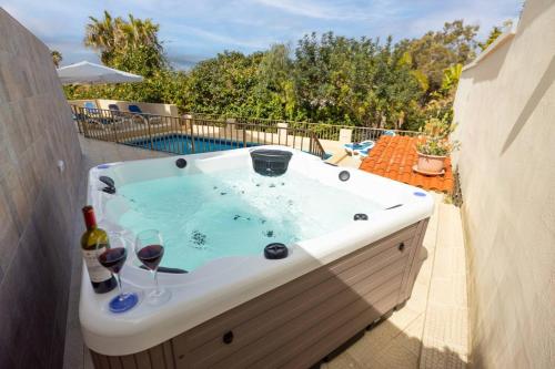 a hot tub with glasses of wine and wine bottles at Villa Lorella - Private Pool, Jacuzzi By Homely in Mellieħa
