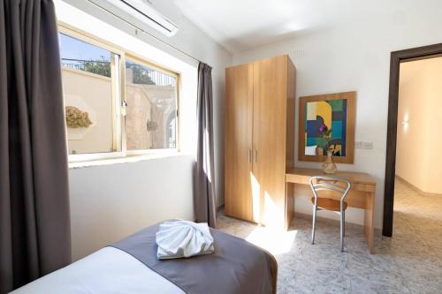 a bedroom with a bed and a desk and a window at Villa Lorella - Private Pool, Jacuzzi By Homely in Mellieħa