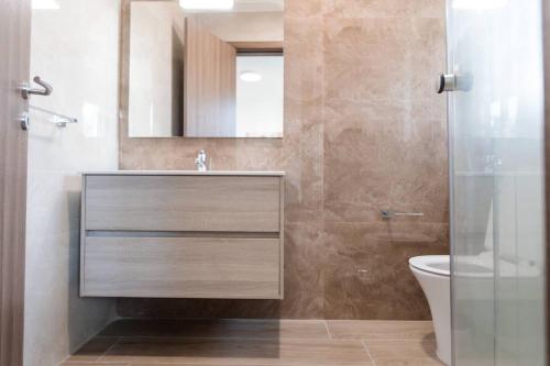 a bathroom with a sink and a toilet and a mirror at Luxe 3br Melliehabay Stunning Terrace By Homely in Mellieħa