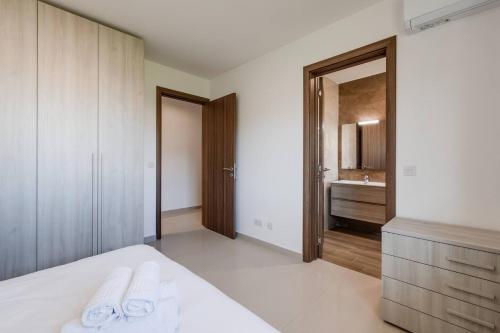 a bedroom with a bed and a bathroom with a sink at Luxe 3br Melliehabay Stunning Terrace By Homely in Mellieħa