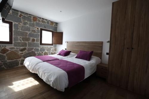 a bedroom with a large bed with purple pillows at Casa rural El Atardecer in Villacastín