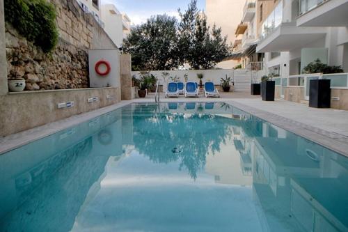a swimming pool with two blue chairs in a building at 3Bed Mellieha with shared heated pool by Homely in Mellieħa