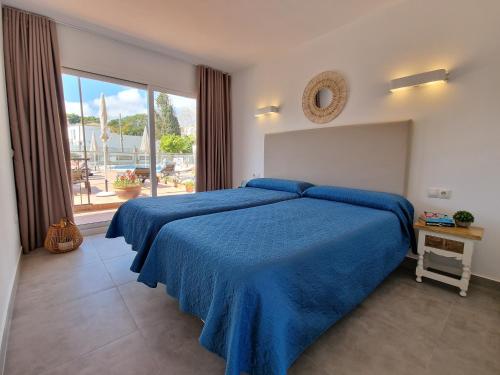 a bedroom with a blue bed with a large window at Apartamentos La Baranda in Torremolinos