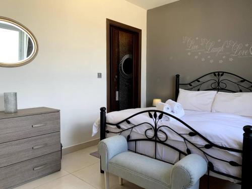 1 dormitorio con 1 cama con silla y espejo en Pearlcourt 1 Bedroom Ph Mellieha, en Mellieħa