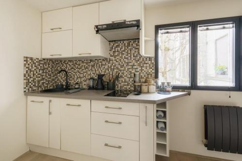 une cuisine avec des armoires blanches et un évier dans l'établissement Central & Stylish 1BD Duplex w GardenMontmartre!, à Paris
