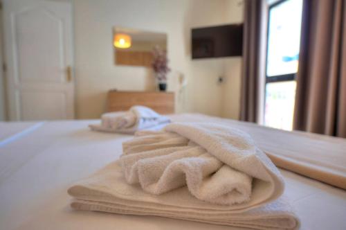 een stapel handdoeken bovenop een bed bij Jonathan Cassar St Julians Lovely 3 Bedrooms in Taʼ Ċikkun