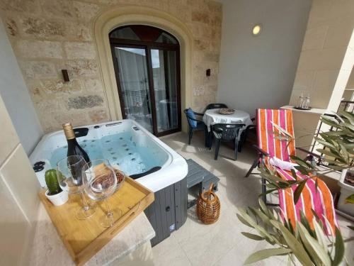a large room with a tub with a bottle of wine at Fl 2 Ta'lonza Luxury With Hot Tub By Homely in Mellieħa