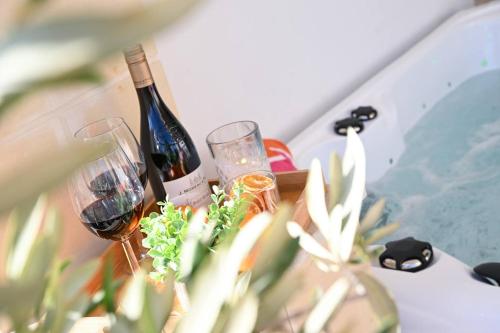 a bottle of wine and two glasses on a table at Fl 2 Ta'lonza Luxury With Hot Tub By Homely in Mellieħa