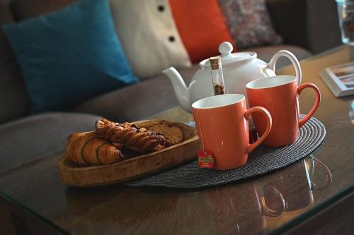 a table with two coffee cups and a tray of pastries at Fl 2 Ta'lonza Luxury With Hot Tub By Homely in Mellieħa