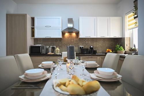 a kitchen with a table with plates and wine glasses at Ta'lonza2 Prime Location Reach Most Of The Island in Mellieħa