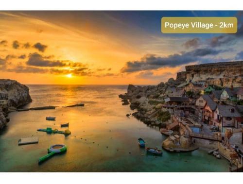 a sunset over a beach with boats in the water at Fl 2 Ta'lonza Luxury With Hot Tub By Homely in Mellieħa