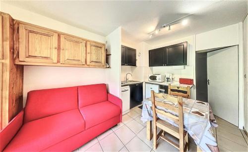 un salon avec un canapé rouge et une cuisine dans l'établissement Résidence Cosmos - STUDIO 4 PERSONNES COSMOS MAE-9634, au Corbier