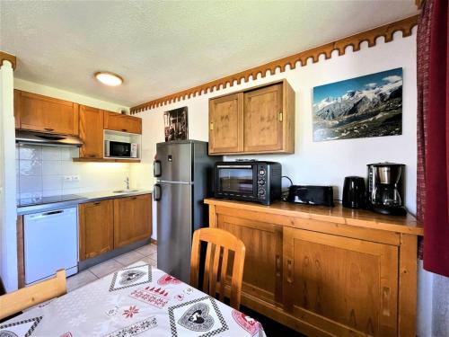 une cuisine avec un réfrigérateur en acier inoxydable et une table dans l'établissement Résidence Bosson - Appartement 8 personnes ski aux pieds aux Ménuires MAE-3814, aux Menuires