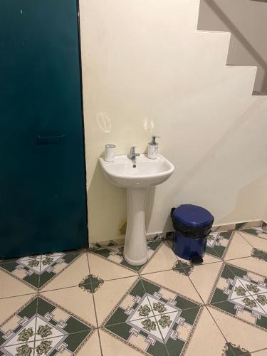 ein Badezimmer mit einem Waschbecken und einem blauen Mülleimer in der Unterkunft Casa El Majahual in Playa San Blas